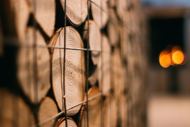 背景がぼやけた金網柵で覆われた積み重ねられた木の材木の選択的な焦点