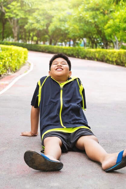 Избирательный фокус на молодом азиатском мальчике, сидящем и уставшем на трассе после бега