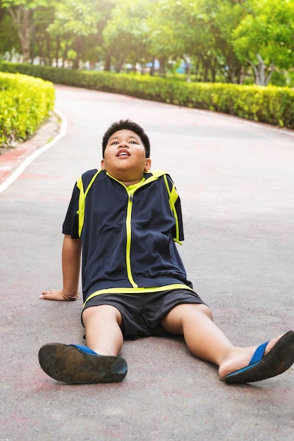 Free photo selective focus at young asian boy sit and tired on track after running