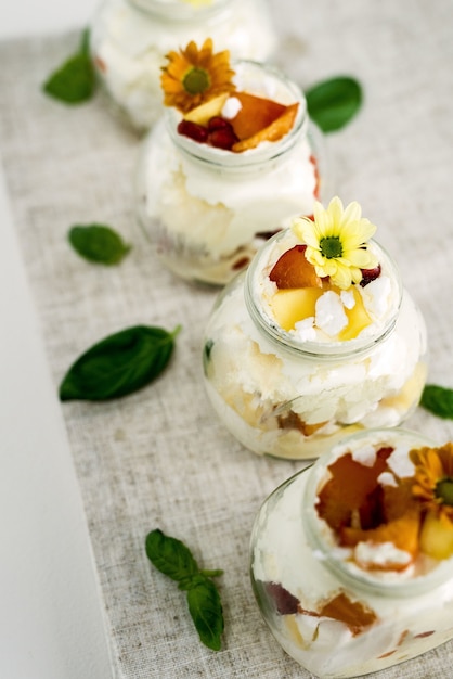 Selective focus of yummy and sweet vanilla ice cream in glass jars decorated with yellow flowers