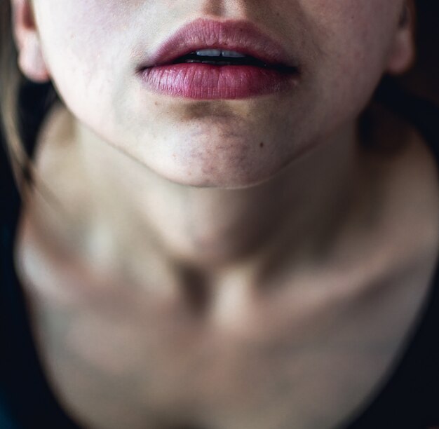 淡い肌と見上げる乾燥したピンクの唇を持つ女性の選択的なオーバーヘッドのクローズアップショット