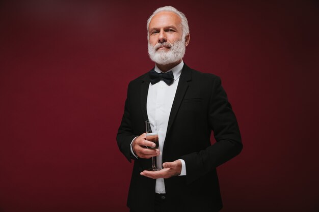 Self confident man in black suit holding champagne glass