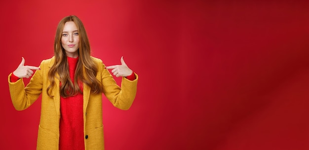 Foto gratuita affascinante imprenditrice sicura di sé, assertiva e ottimista con i capelli rossi in cappotto giallo po