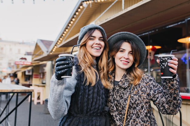 Selfie portrait of joyful fashionable women having fun on sunny street in city. Stylish look, having fun, travelling with friends, smiling, expressing true positive emotions.