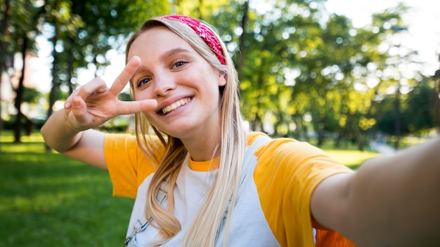 Selfie of smiley woman making peace sign