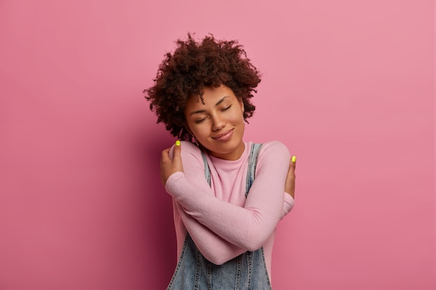 Foto gratuita la donna dai capelli ricci egoista abbraccia e ama se stessa