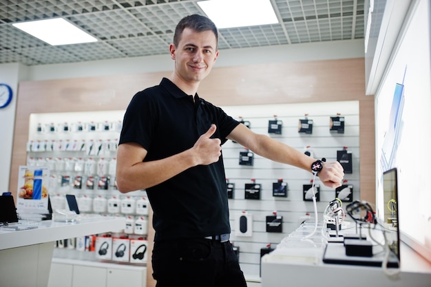기술 상점 또는 상점의 판매자 남자 휴대 전화 전문 컨설턴트는 새로운 스마트 시계를 확인합니다.