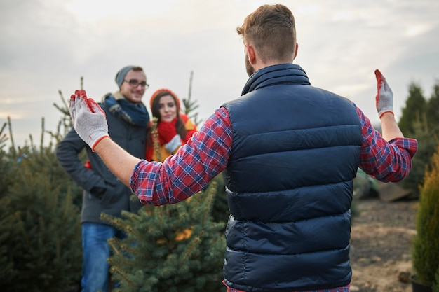 Foto gratuita venditore che mostra le dimensioni dell'albero