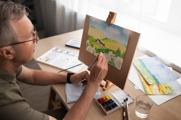 Foto gratuita artista senior in studio di pittura con acquerello