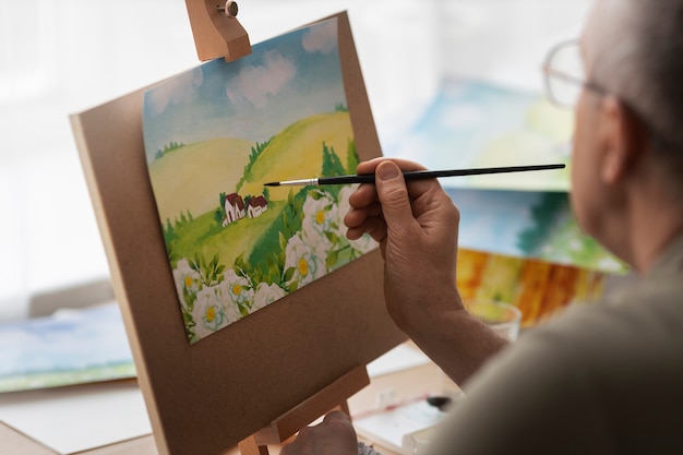 Foto gratuita artista senior in studio di pittura con acquerello