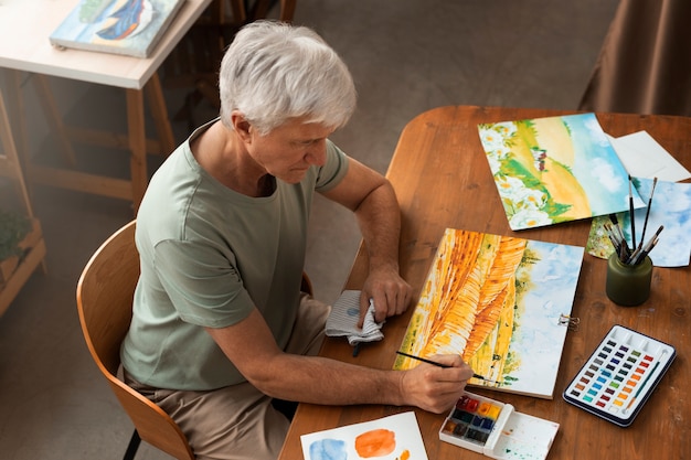 Foto gratuita artista senior in studio di pittura con acquerello