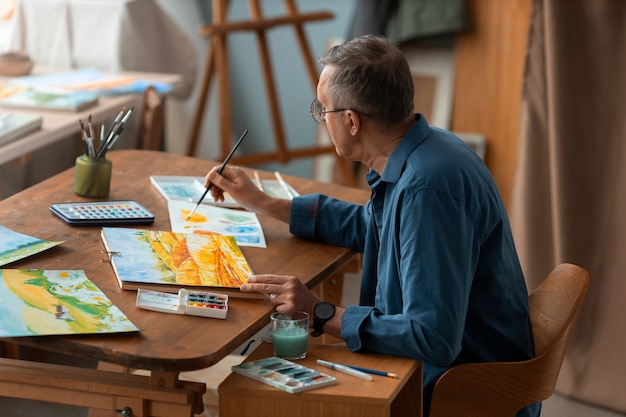 Free photo senior artist in the studio painting with watercolor