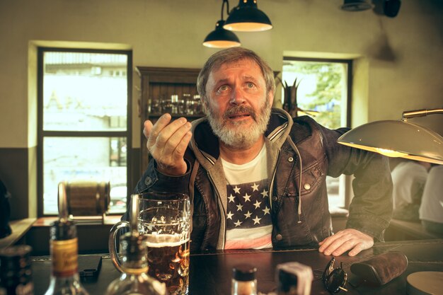 The senior bearded male drinking beer in pub