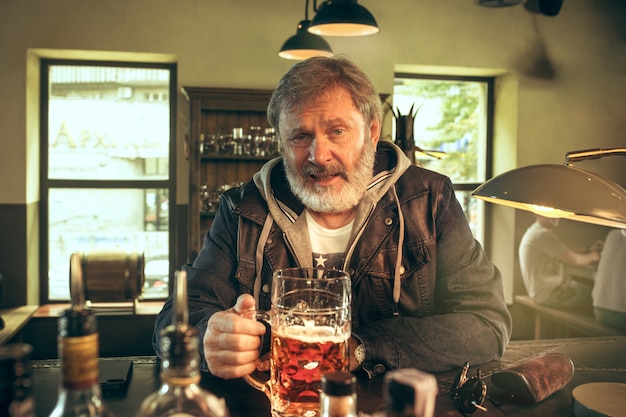 Foto gratuita il maschio barbuto senior che beve birra in pub