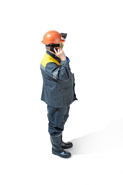 Free photo senior bearded male miner standing at the camera on a white