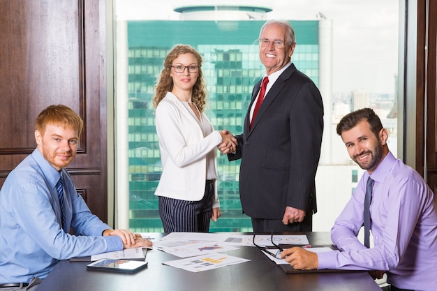 Senior business man smiling while shaking hands with a woman