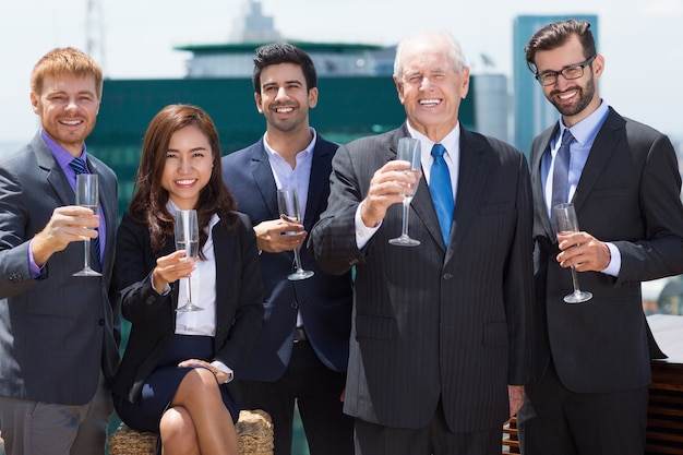 Senior business man with more business people with champagne glasses
