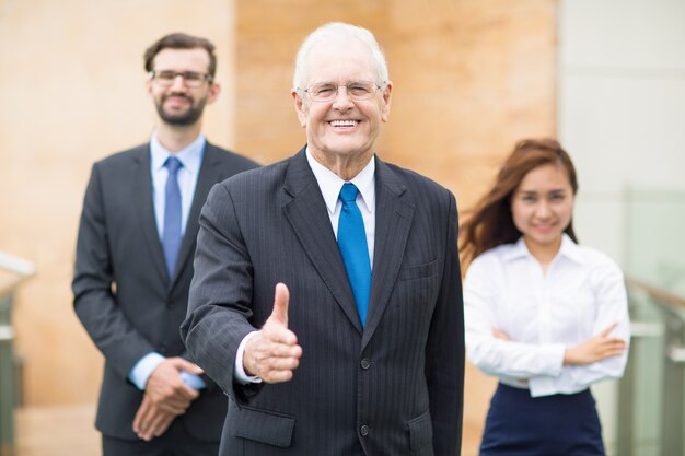 Старший деловой человек с поднятой пальца вверх улыбается