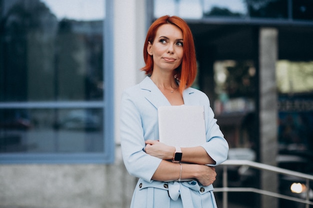 Senior business woman with laptop by office center