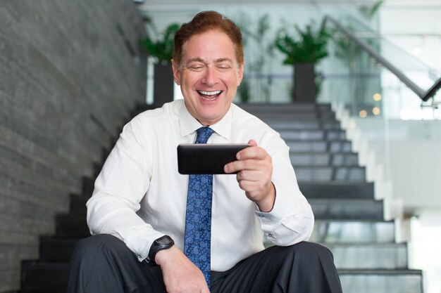 Senior businessman laughing at internet video