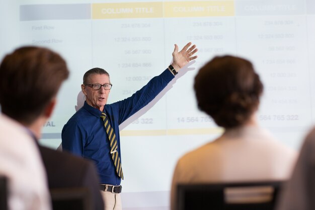 Senior Businessman Showing Table to Audience