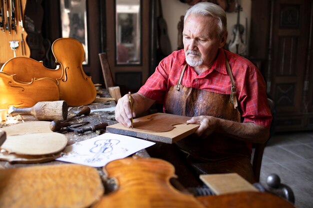 Senior carpenter craftsman making violin music instrument in his old-fashion carpenter's workshop