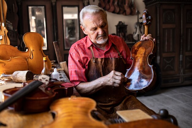 彼の大工のワークショップでバイオリン楽器を磨く上級大工職人