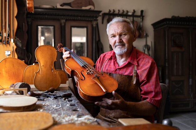 彼が作成したバイオリン楽器を示すシニア大工