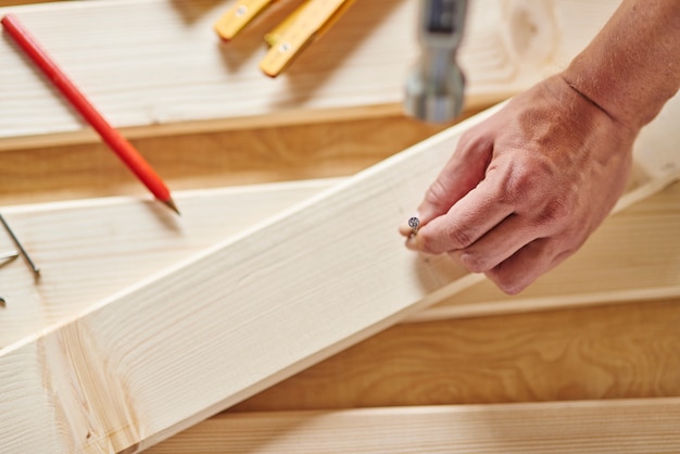 Free photo senior carpenter tries to hammer the nail