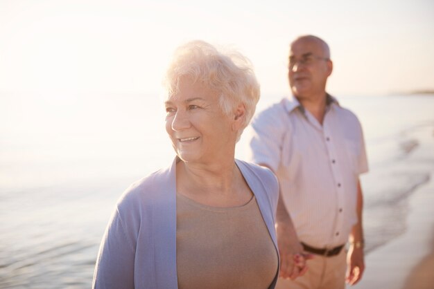 Старшая пара на пляже, пенсия и летние каникулы концепции