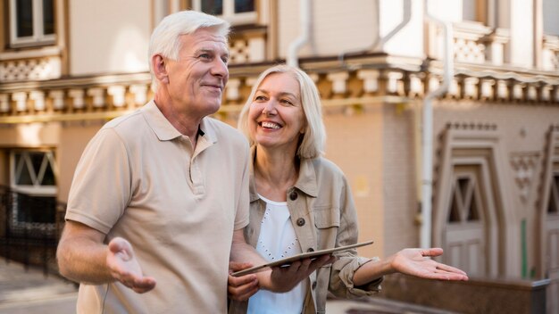 Senior couple being lost while out in the city and holding tablet