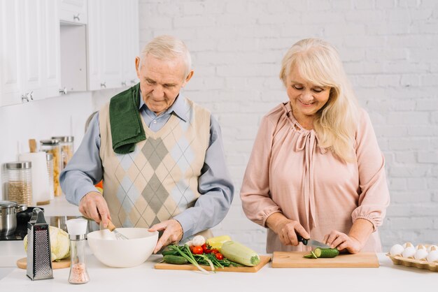 Пожилая пара готовит еду на кухне