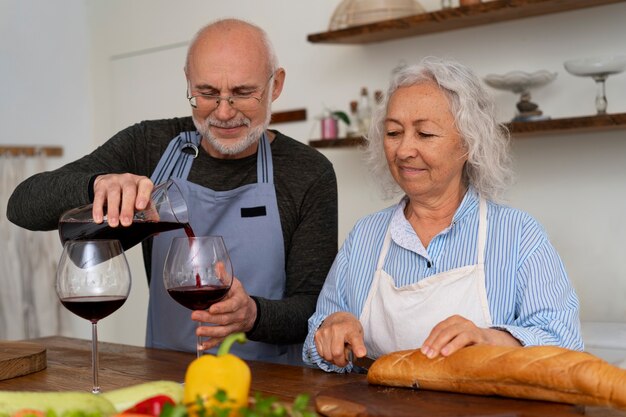 キッチンで一緒に料理を作り、ワインを飲むシニア夫婦