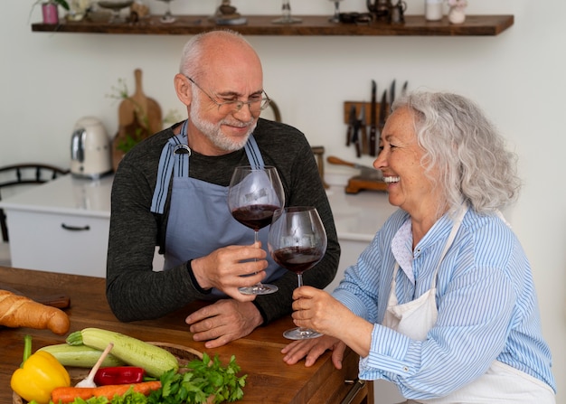 Foto gratuita coppia anziana che cucina insieme in cucina e beve vino