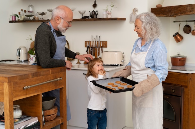 Free photo senior couple cooking together in the kitchen with grandchild