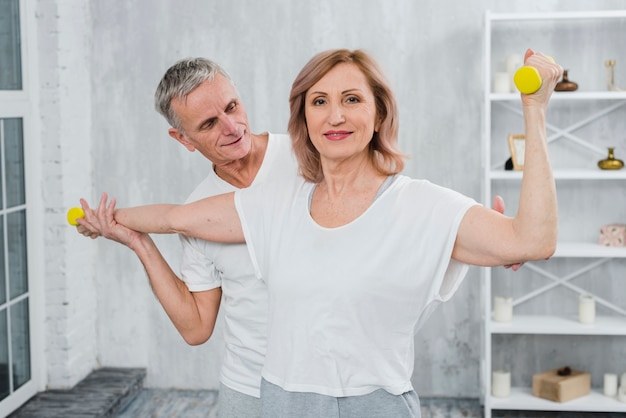 Senior couple exercising together at home with dumbbells