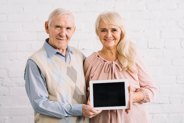 Пожилая пара держит планшет