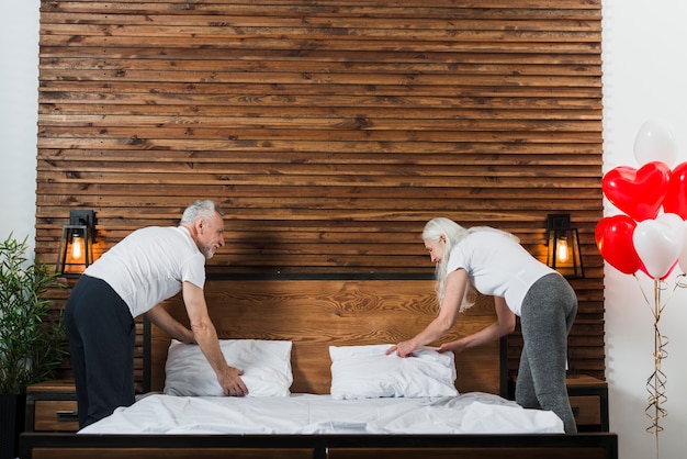 Senior couple making bed together