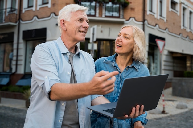 Senior couple outside in the city while holding laptop