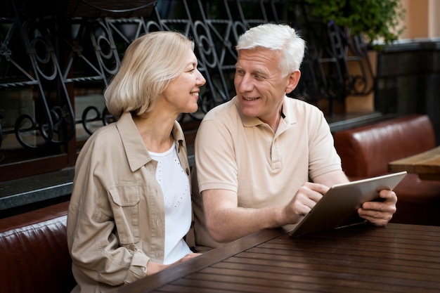 Free photo senior couple sitting down while out in the city with tablet