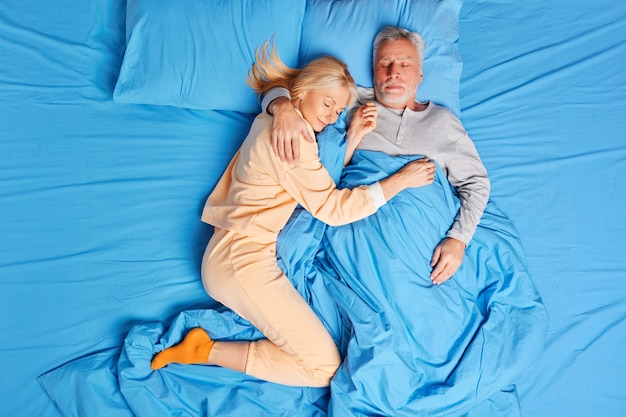 senior couple sleep peacefully together in bed embrace and and have healthy nap rest at home during early morning lying asleep. Bedtime family and relaxation concept