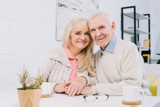 Senior couple at table holding hands