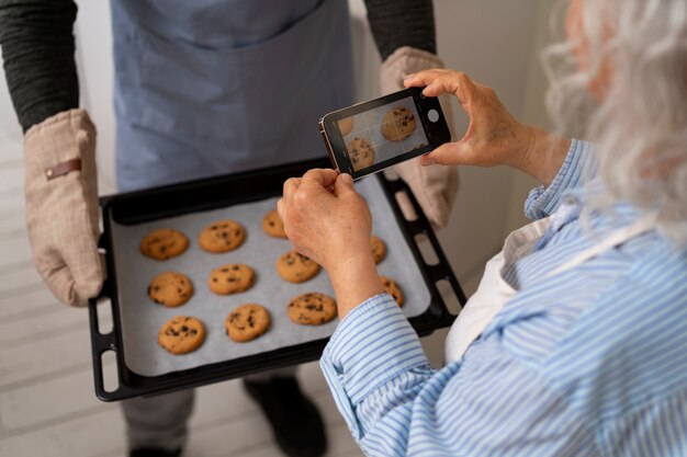 キッチンでクッキーの写真を撮るシニア夫婦