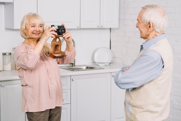 Free photo senior couple taking photo in kitchen