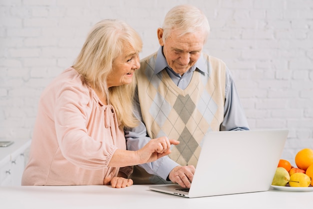 Senior couple with laptop in kitchen