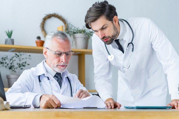 Free photo senior doctor showing papers to young colleague