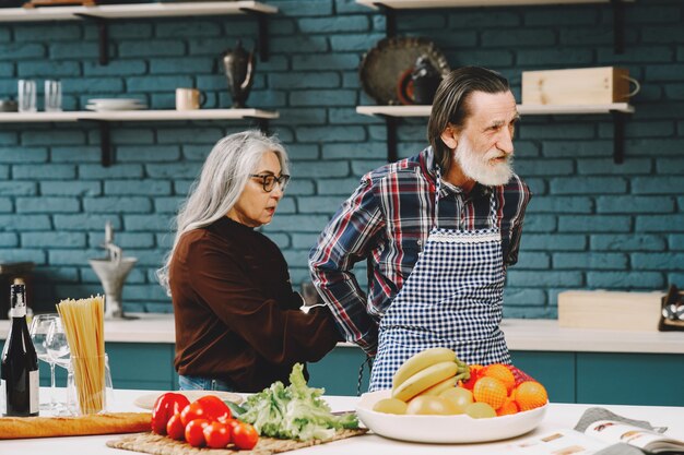 Senior european race couple putting on aprons in kitchen