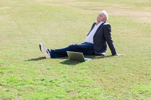 Free photo senior executive resting on the grass