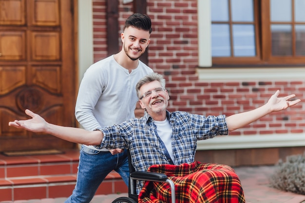 Free photo senior father in wheelchair and young son on a walk