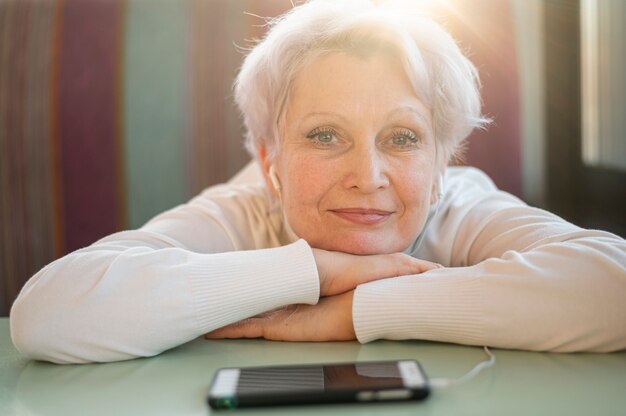 Senior female sitting with head on table and listening music